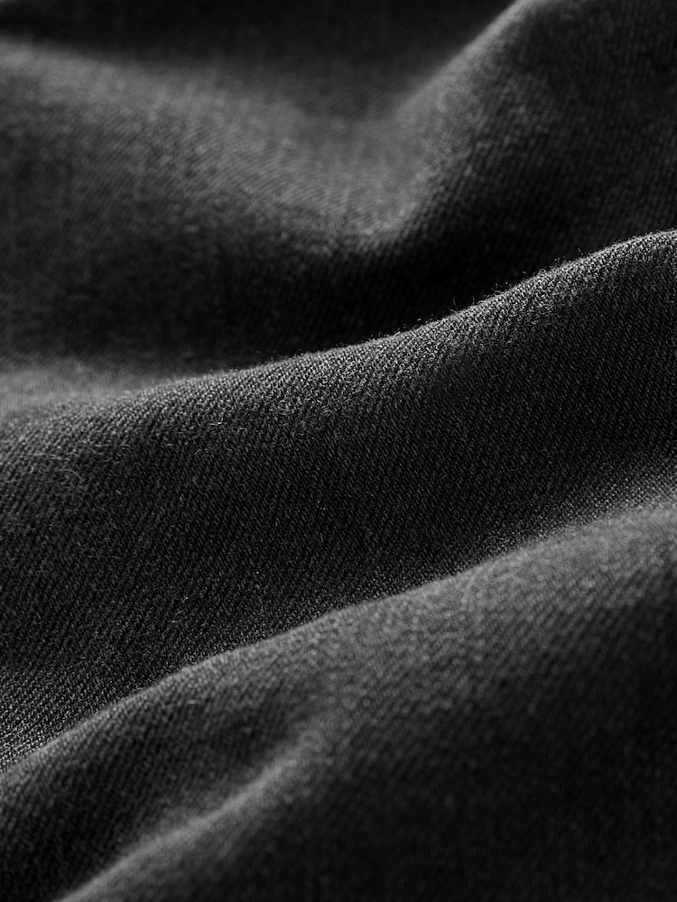 Close-up of black ISKO BLUESKIN stretch denim fabric from Zalemart showing the textured weave and material quality.